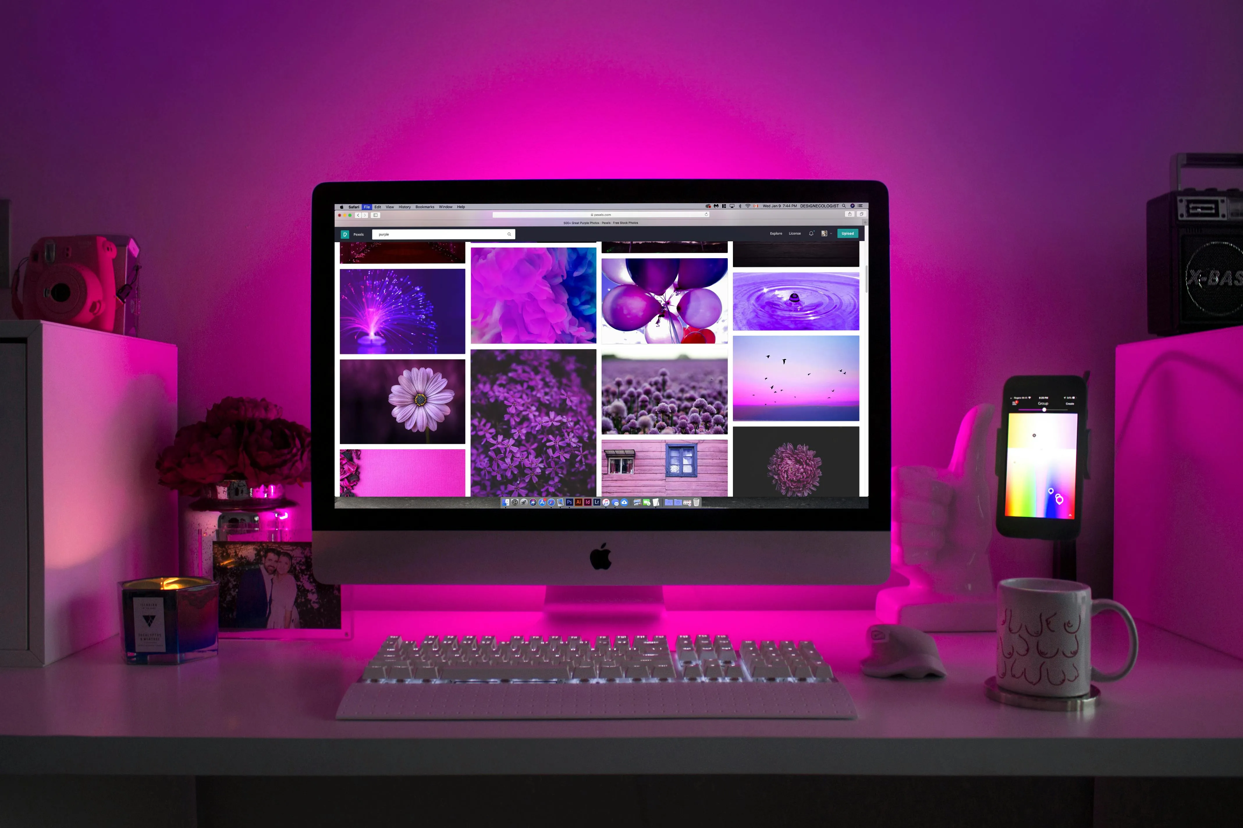 Desk with monitor, candle, flowers, and smartphone.