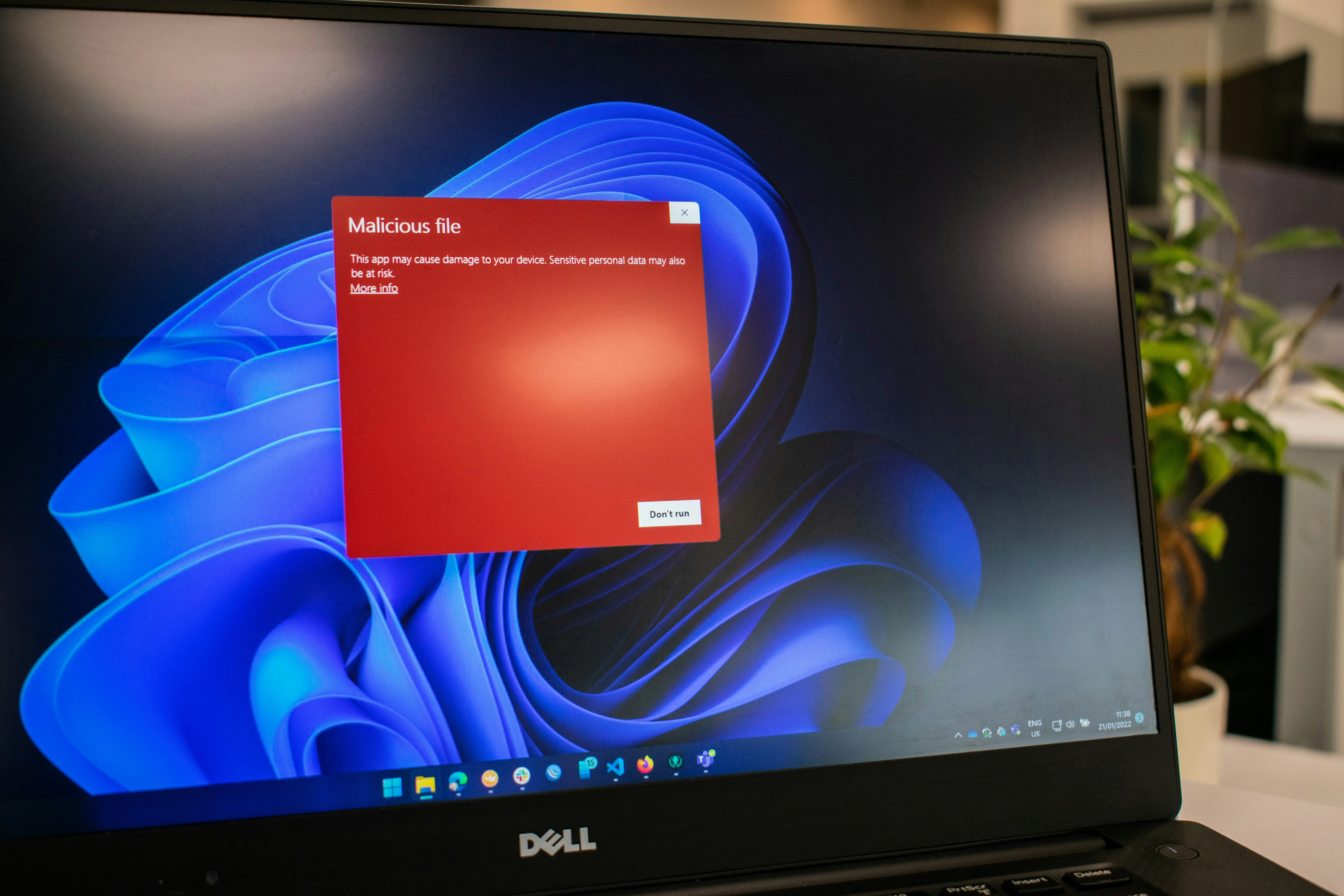 Laptop screen showing a red malicious file warning.​​