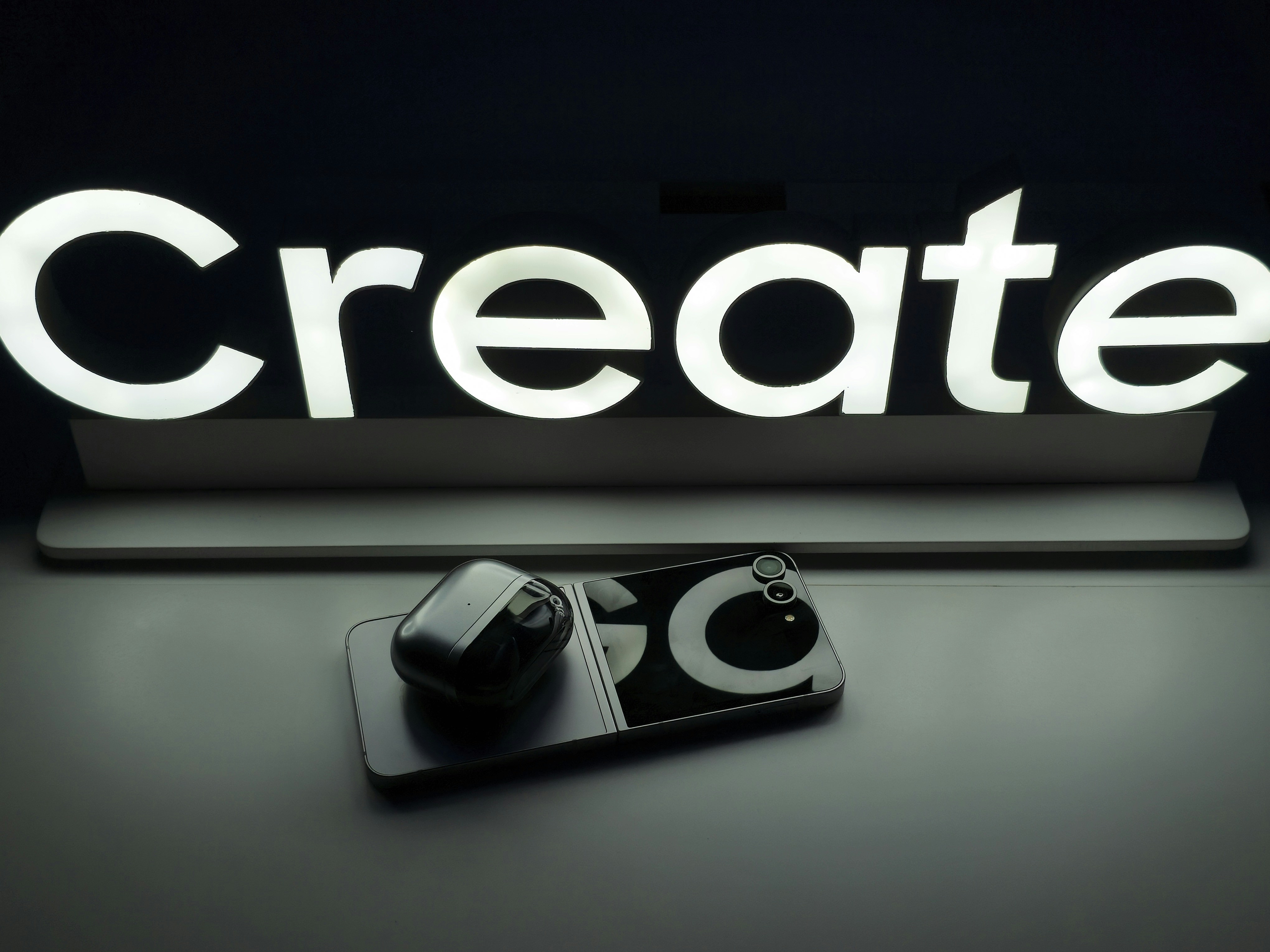Create' sign above a smartphone with wireless earbuds