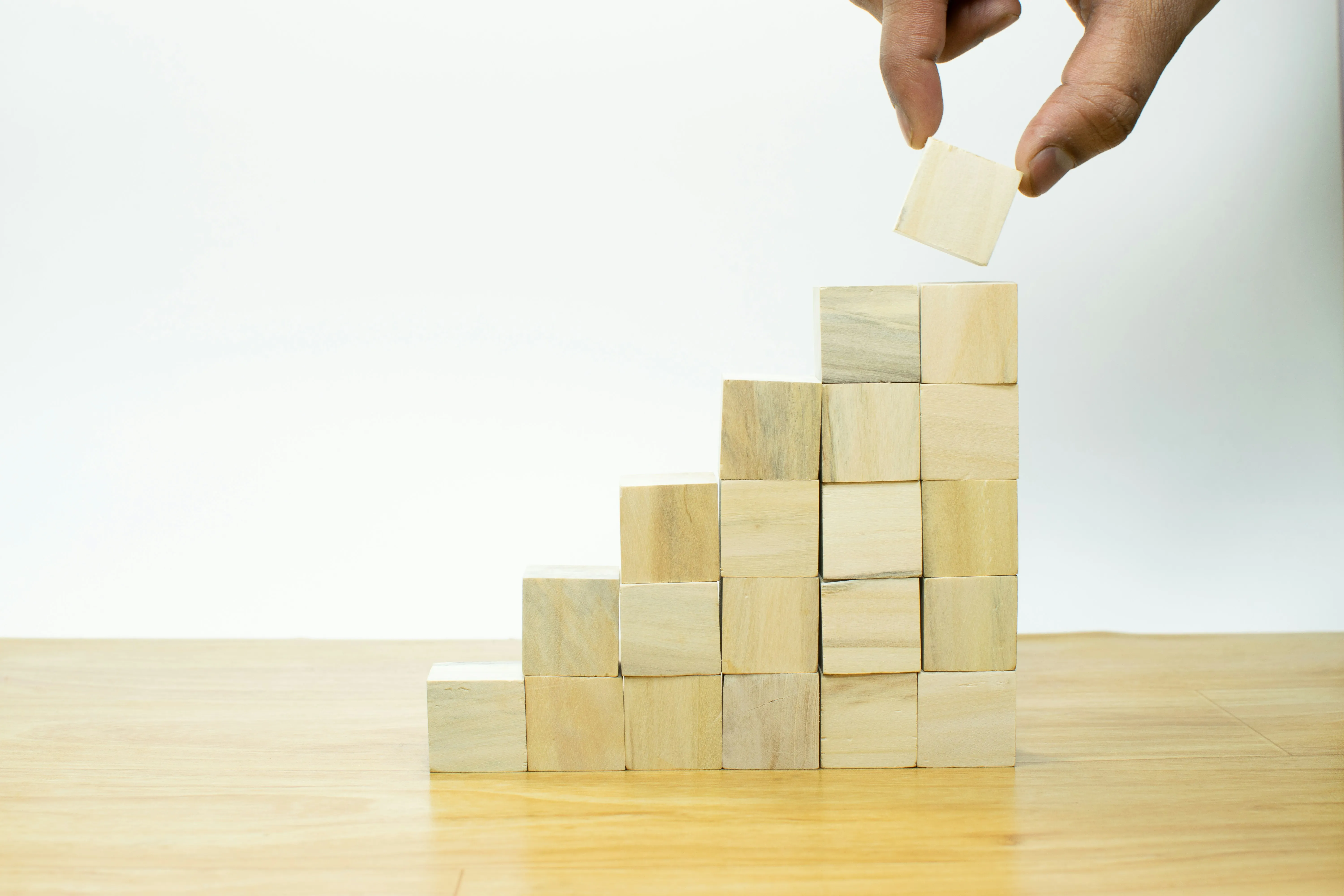 Hand adding a block to a wooden staircase.