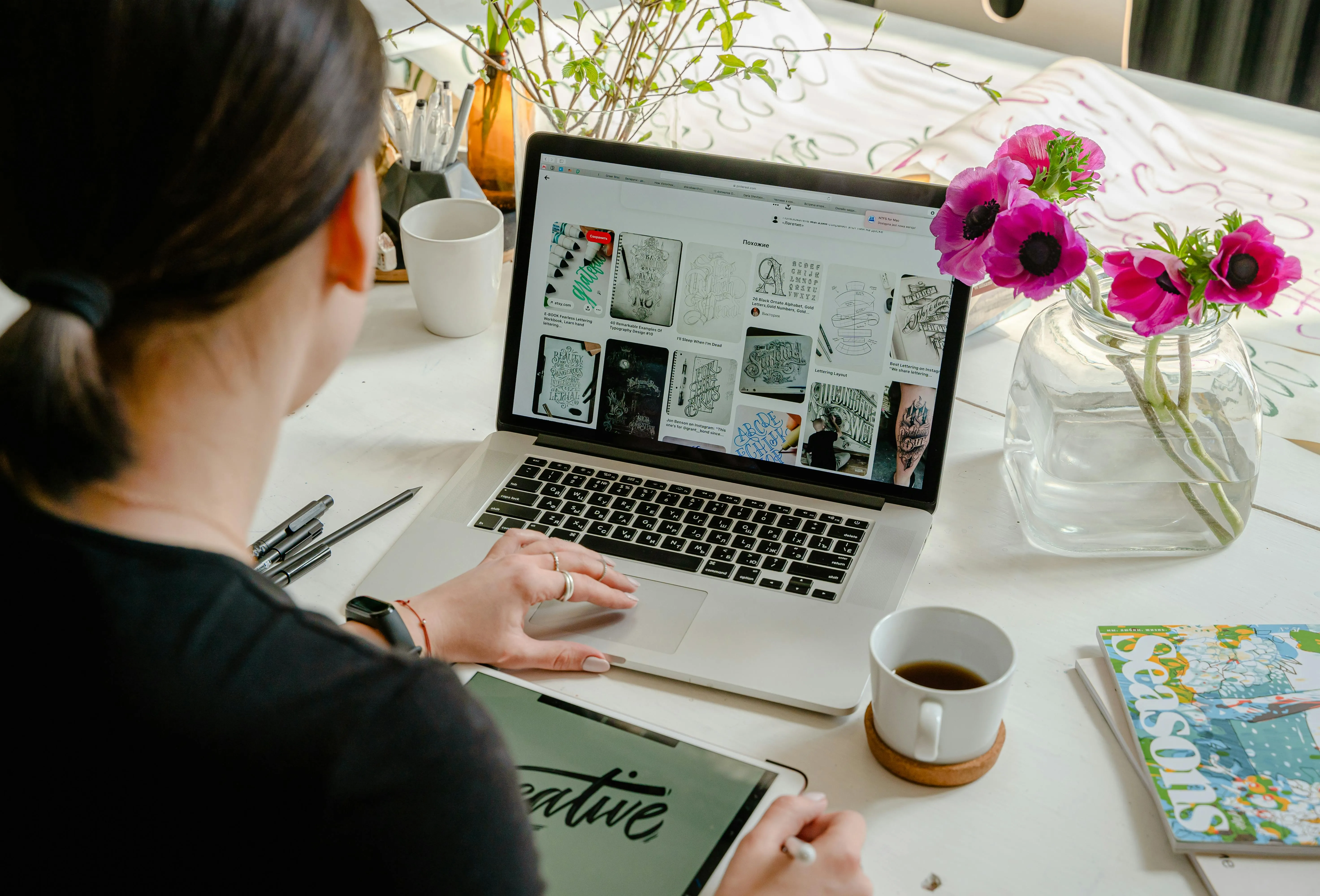 Creative workspace with laptop, tablet, and flowers.