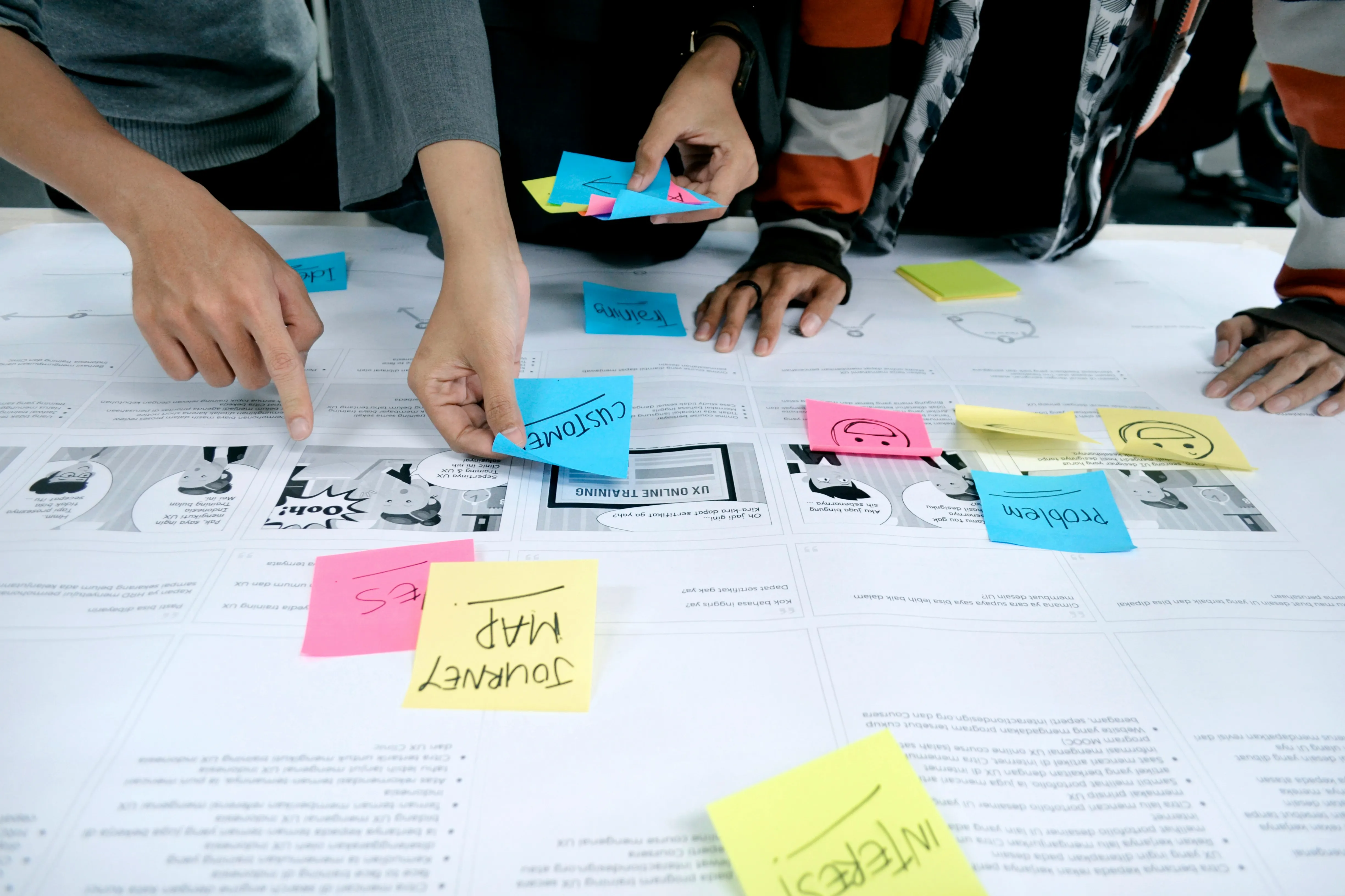 Sticky notes and hands in brainstorming session.