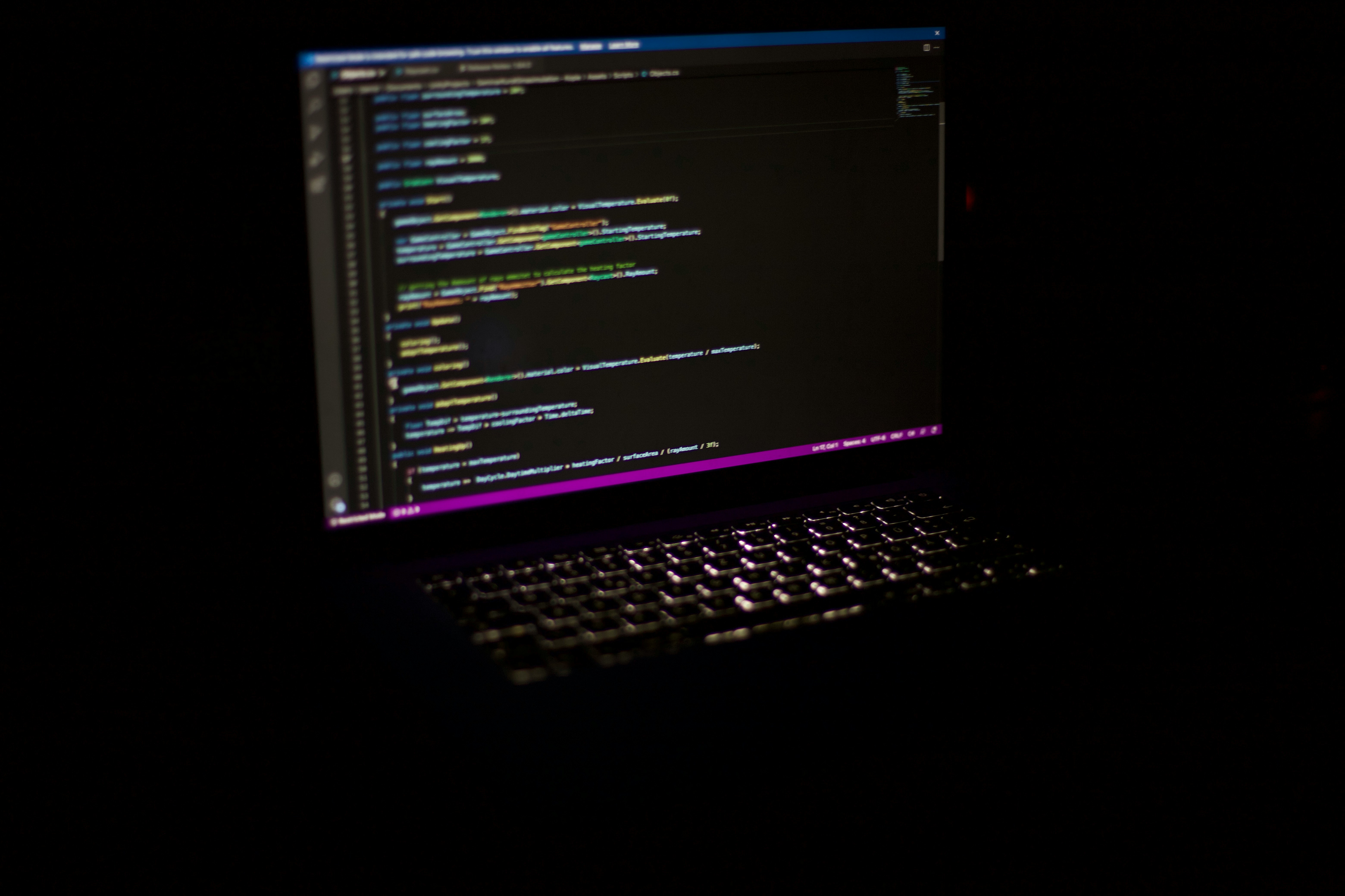 Laptop screen showing code in a dark room.