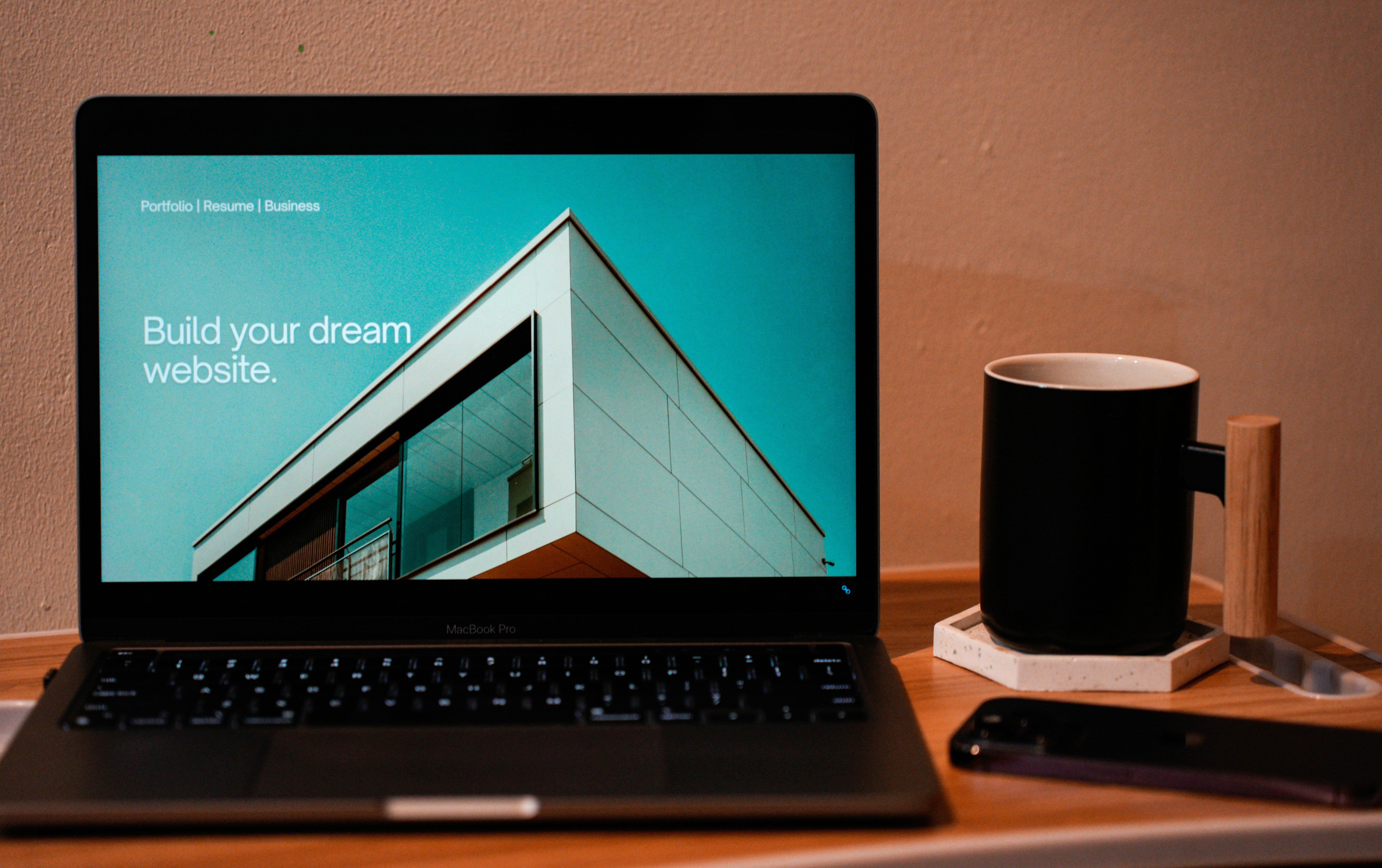 Laptop showing a website, with a black mug and smartphone on a wooden desk