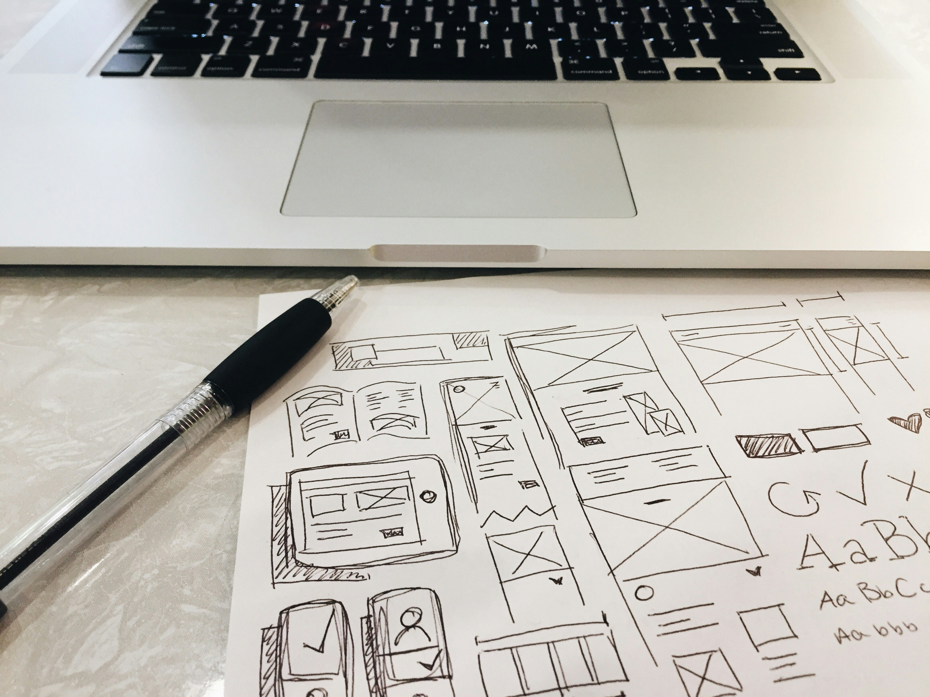 Laptop and hand-drawn wireframe sketches on paper