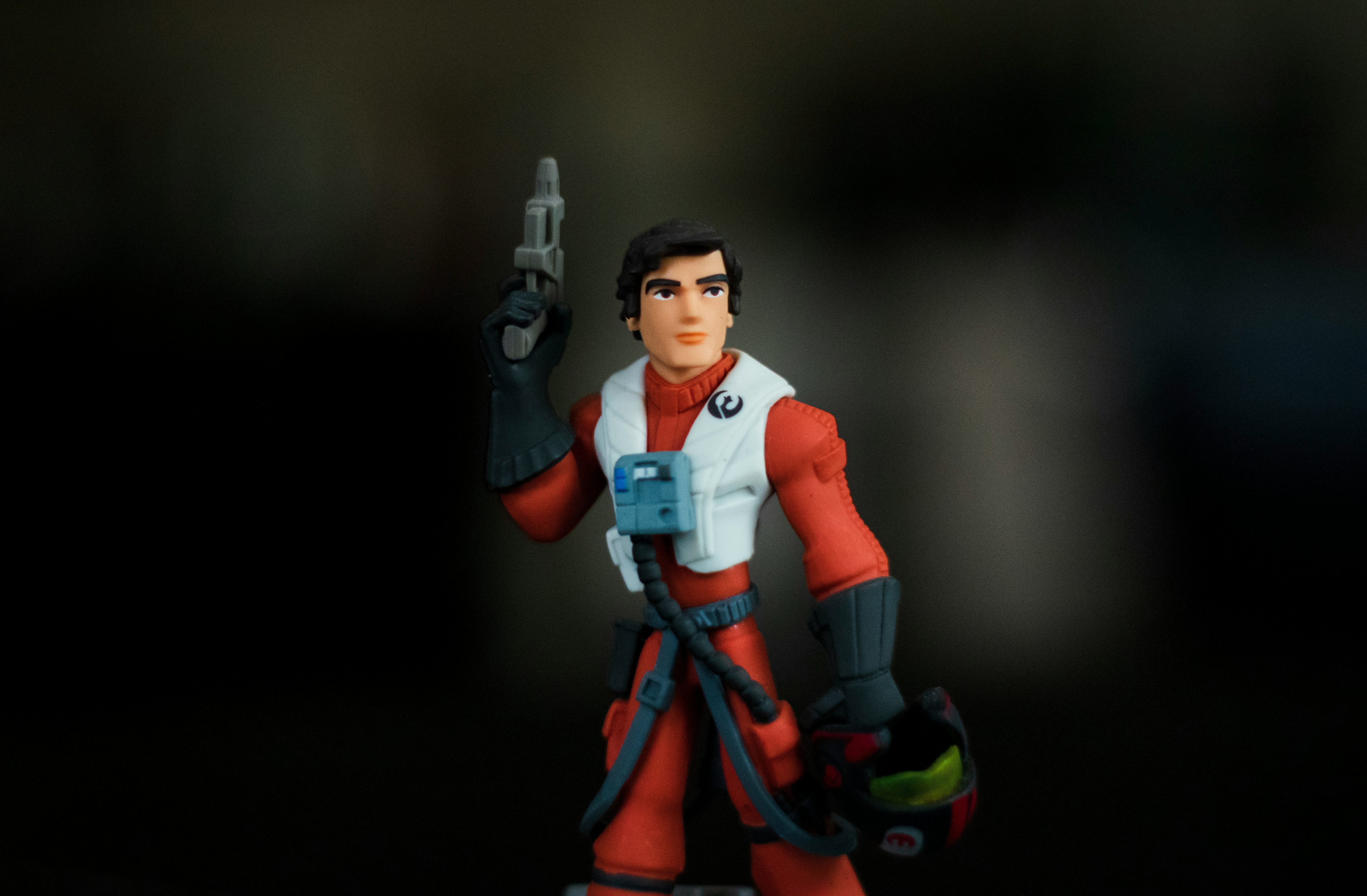 Action figure in a red suit holding a helmet.