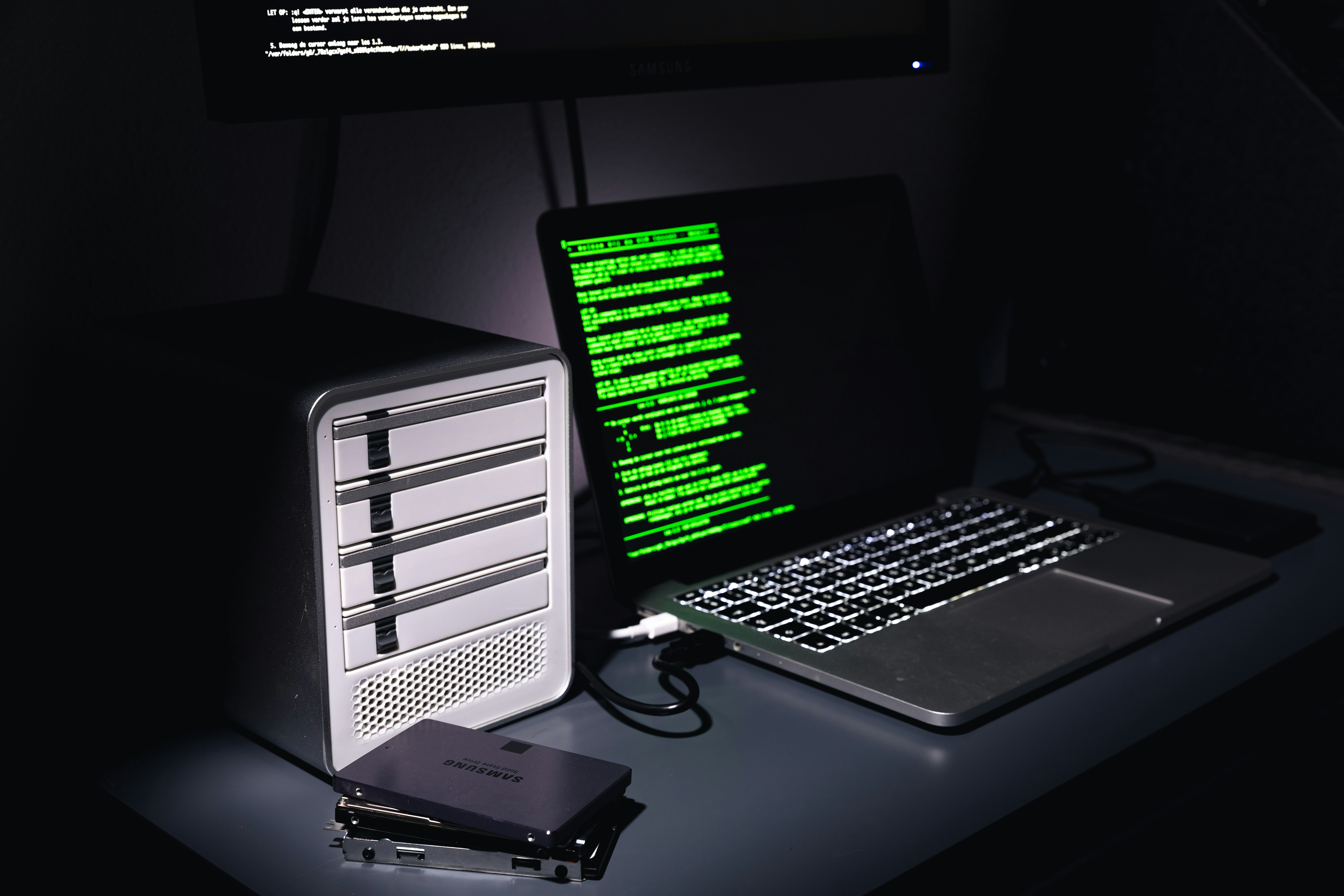 Laptop displaying green terminal text, surrounded by storage devices, representing data security